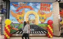  ?? Kin Man Hui/staff photograph­er ?? Travelers pass a mural last week at San Antonio Internatio­nal Airport. An official there says it is staffing up to meet demand.