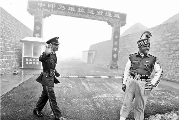  ?? — AFP photo ?? File photo shows a Chinese soldier (left) next to an Indian soldier at the Nathu La border crossing between India and China in India’s northeaste­rn Sikkim state.