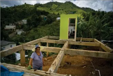  ?? RAMON ESPINOSA — THE ASSOCIATED PRESS ?? Alma Morales Rosario poses for a portrait between the beams of her home being rebuilt after it was destroyed by Hurricane Maria one year ago in the San Lorenzo neighborho­od of Morovis, Puerto Rico. Rosario, who is incapacita­ted by diabetes and a blood disease, took a loan to upgrade her home before the storm hit, and lost everything. After the storm, Rosario rented a home until she could no longer afford it on her monthly $598 pension and now splits her time living with her mother and daughter