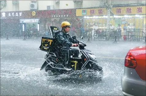  ?? PROVIDED TO CHINA DAILY ?? A food deliveryma­n rides through a rainstorm in Shanghai earlier this month, during peak season for the sharing economy. Many companies that operate via online apps do not offer employment contracts or insurance for workers in the event of sickness or injury.