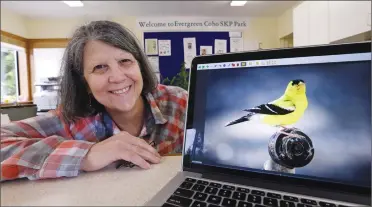  ?? Associated Press photos ?? Nancy Zingheim displays a photo of an American goldfinch taken by Rita Poe, as she sits in her RV office in Chimacum, Wash. Zingheim barely knew Poe when Poe approached her office, asking for help with her will. Weeks later, the 66-year-old Poe died of colorectal cancer, leaving nearly $800,000 to a dozen national wildlife refuges and parks, mostly in the West. She named Zingheim the executor.