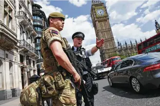  ?? Justin Tallis / AFP / Getty Images ?? A British Army soldier patrols with an armed police officer near the Houses of Parliament in London on Wednesday. Armed forces near landmarks illustrate­d the gravity of the threat.