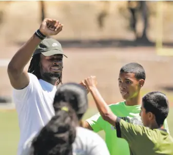  ?? Carlos Avila Gonzalez / The Chronicle ?? Najee Harris high-fives kids after they completed drills during Saturday’s Purpose Filled Youth Outreach leadership camp, whose purpose was faith-based leadership skills building.