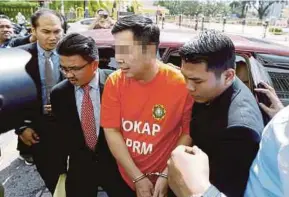  ?? PIC BY RAMDZAN MASIAM ?? The deputy chairman of a property developmen­t company being escorted by MACC officers to the magistrate’s court in George Town yesterday.