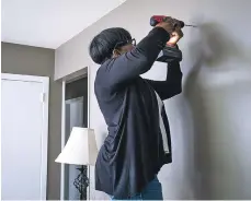  ??  ?? Sandiford uses a drill as she prepares to hang decorative items on her living room wall in Brentwood, N.Y. Maintenanc­e classes can teach you how to use such tools, and they can help you save money and be smarter about what needs to be done to keep your new home in shape.