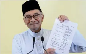  ?? — AZHAR MAHFOF/THE Star ?? Unity in diversity: Anwar displaying a list of new Cabinet members on Friday night. The lineup has been welcomed as a reflection of the diverse unity government that the Rulers had suggested.