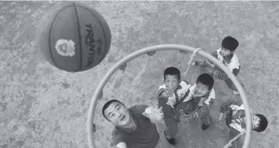  ?? CHEN BIN / XINHUA ?? Wang Fengfeng plays basketball with pupils at Nanqi Primary School.