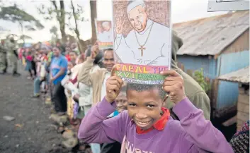  ?? AP ?? A boy holds a picture of Pope Francis as he awaits his arrival at the St Joseph the Worker Catholic Church in the Kangemi slum of Nairobi yesterday.