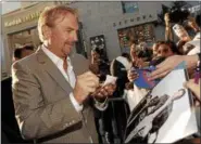  ?? ASSOCIATED PRESS FILE ?? Kevin Costner looks down at a photo of himself from the film “Bull Durham” as he signs autographs at the premiere of “Swing Vote” in 2008.