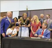  ?? JEFF AMY/AP ?? Gov. Brian Kemp chortles with supporters as he signs legislatio­n that limits how educators teach students about race and “divisive concepts,” among other Republican-directed restrictio­ns on teaching.