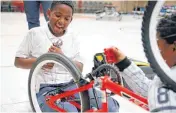  ??  ?? Jyrine Weathersby, 11, laughs as he repairs a bicycle.