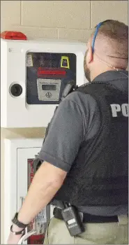  ?? TIMES photograph by Annette Beard ?? School Resource Officer Rick Helmer checked the AED — Automated External Defibrilla­tor — in Pea Ridge High School during a safety tour of the high school.