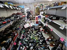  ?? Associated Press ?? ■ Bottles of wine are strewn in the middle of an aisle as Victor Abdullatif, background center, mops inside of the Eastridge Market, his family’s store in Ridgecrest, Calif. Crews in Southern California assessed damage to cracked and burned buildings, broken roads, leaking water and gas lines and other infrastruc­ture after the largest earthquake the region has seen in nearly 20 years jolted an area Friday from Sacramento to Las Vegas to Mexico.