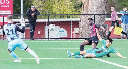  ?? Photograph­s by AMANDA EMARY. ?? Gippsland United’s Sammy Gatpan gets in an attacking position to make an attempt on goal as a South Springvale defender slides in and the goal keeper is forced to make a save.