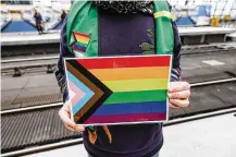  ?? TNS OMER MESSINGER/GETTY IMAGES/ ?? A volunteer holds a “Progress Pride Flag.”