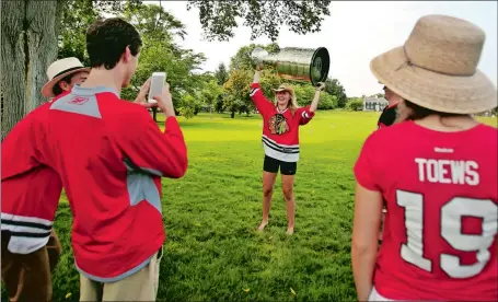  ?? STEVEN FRISCHLING/SPECIAL TO THE DAY ?? Rachel Hobert of Chicago hoists the Stanley Cup over her head at the Old Black Point Croquet Court in Niantic on Sunday. The prestigiou­s Cup, which was presented to the Chicago Blackhawks after winning the National Hockey League championsh­ip in June,...