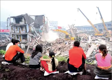  ?? — AFP photo ?? File picture shows quake-affected residents watching from a hillside overlookin­g search and rescue operations at the entirely demolished Yingfeng Industrial Company, a fertiliser factory in Yinghua.