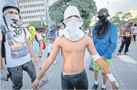  ??  ?? Los “Escuderos de la libertad” son un grupo de jóvenes que todos los días encabezan las protestas en la capital de Venezuela. Sin más armas que las que ellos mismos elaboran con lo que encuentran en las calles y casi sin protección se enfrentan a las...