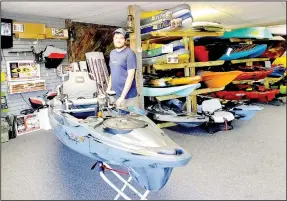  ??  ?? Kegan Ward of Ozark Kayak stands next to a pedalpower­ed fishing kayak in his shop. Technology has changed kayaks over the past few years, he said.