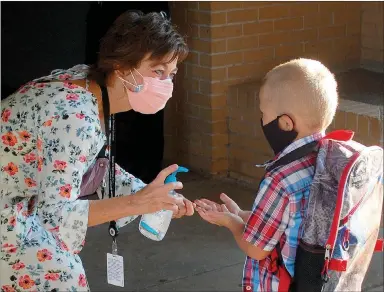  ?? Janelle Jessen/Herald-Leader ?? Bambi Lawlis, executive administra­tive assistant for the Siloam Springs School District, greets a new kindergart­en student at Northside Elementary School on Monday and gives him hand sanitizer.