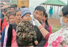  ?? — AFP ?? A member of medical staff wearing a facemask checks the body temperatur­e of travellers arriving from Nepal at the India-nepal border at Panitanki checkpoint, some 32km from Siliguri, on Saturday.