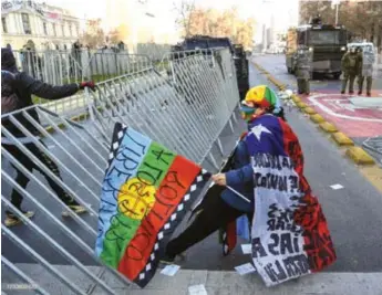  ??  ?? Des manifestan­ts abattent une clôture lors d’une marche en direction du Congrès national chilien où se tient la première session de l’Assemblée constituan­te, à Santiago