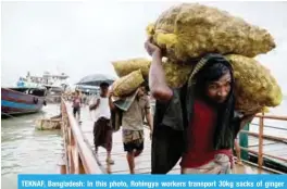  ?? — AFP ?? TEKNAF, Bangladesh: In this photo, Rohingya workers transport 30kg sacks of ginger from a boat, which arrived from Myanmar’s Rakhine state, to waiting trucks at Teknaf port near Cox’s Bazar.