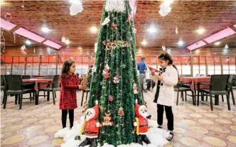  ??  ?? Palestinia­n children decorate a Christmas tree at a restaurant in Gaza City on Monday.