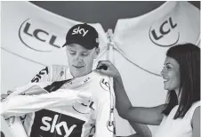  ?? THE ASSOCIATED PRESS ?? Britain’s Chris Froome puts on the overall leader’s yellow jersey on the podium after the 15th stage of the Tour de France on Sunday.