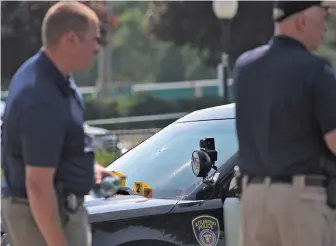  ?? Staffphoto­sbyfaithni­nivaggi ?? ‘GRACE OF GOD’: Officials pass an Attleboro police cruiser covered with evidence markers and bullet holes in the windshield. An armed man allegedly was found inside the South Attleboro Assembly of God, far left, before shooting at police yesterday.