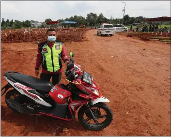  ??  ?? Hendi, a motorcycle volunteer, stands by his motorcycle after escorting an ambulance carrying the body of a covid-19 victim for burial at Pedurenan cemetery in Bekasi.
