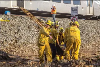  ?? Austin Dave/The Signal ?? (Above) Los Angeles County firefigher­s carry a passenger with a medical issue through mud after a Metrolink train stopped in Acton due to track integrity problems. (Below) A man in an Izuzu Trooper drives through deep floodwater on Crown Valley Road...