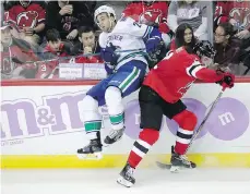  ?? JULIO CORTEZ/THE ASSOCIATED PRESS ?? Devils defenceman John Moore checks Canucks centre Brandon Sutter on Friday night.