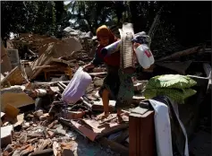  ??  ?? A woman carries usable items from the ruins of her house in Kayangan district after the Lombok earthquake. – Reuters photos