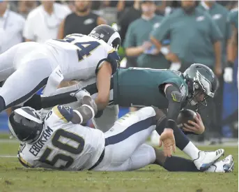  ??  ?? Les quart des Eagles de Philadelph­ie, Carson Wentz, se fait plaquer par deux joueurs défensifs des Rams de Los Angeles, dimanche. - Associated Press: Mark J. Terrill