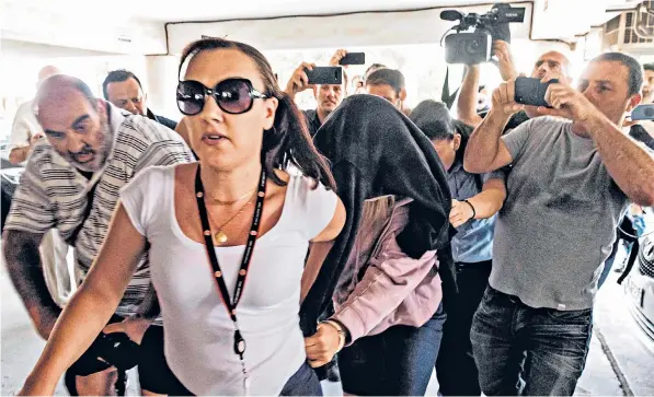  ??  ?? The British woman is escorted into court in Paralimni in eastern Cyprus for a hearing in her trial on charges of fabricatin­g a claim of gang rape against a group of Israelis. Her stay in Cyprus began in early July in the party town of Ayia Napa, below left