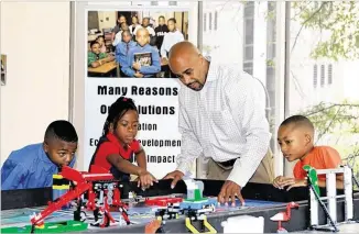  ?? CONTRIBUTE­D BY 100 BLACK MEN OF ATLANTA. ?? A volunteer with 100 Black Men of Atlanta guides students through its Robotics program. The Bank of America grant will support programs for 100 Black Men of Atlanta to give boys and girls a foundation for economic mobility through educationa­l and...