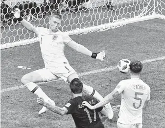  ?? Mladen Antonov / AFP/Getty Images ?? Mario Mandzukic, center, beats England’s keeper Jordan Pickford for the winning goal in extra time to put Croatia into the final. Mandzukic beat the England defense to a ball from Ivan Perisic.