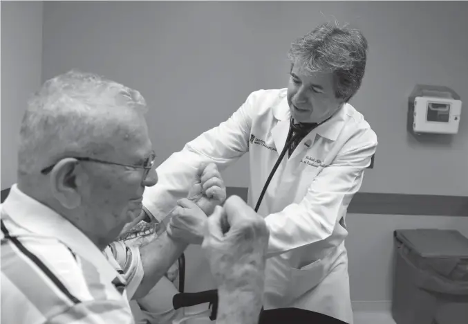  ?? TNS ?? above Dr. Michael Miller, right, a professor of cardiovasc­ular medicine, checks the arm strength of Hank Butta, 89, during a consultati­on at his office at the University of Maryland Medical Center.