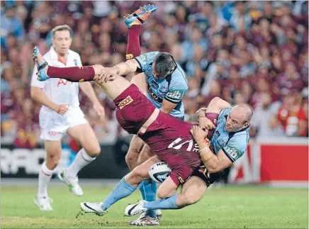  ??  ?? Not a good look: Brent Tate of the Maroons is picked up in the tackle by Josh Reynolds and Beau Scott of the Blues during game one of the State of Origin series on Wednesday night. Photo: Getty Images