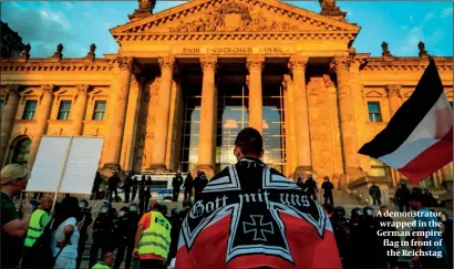  ?? PHOTO: GETTY IMAGES ?? A demonstrat­or wrapped in the German empire flag in front of the Reichstag