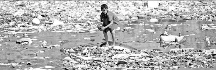  ??  ?? A boy looks for plastic bottles at the polluted Bagmati River in Kathmandu in this file photo. — Reuters photo