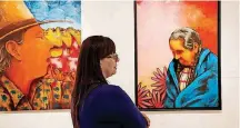  ??  ?? Laura Clark, program manager for Fred Jones Jr. Museum of Art’s “Visual Voices: Contempora­ry Chickasaw Art Exhibition,” stands between two works of art by Brent Greenwood, Chickasaw/Ponca. At left is “The Awakening” (2018); at right is “Gathering Medicine” (2017).