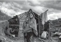  ??  ?? A refugee holds her child as she stands outside her shelter at the sprawling Balukali refugee camp in Cox’s Bazar, Bangladesh.