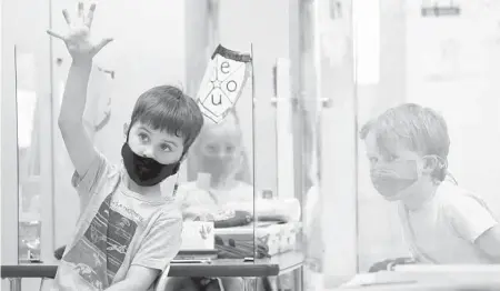  ?? MARY ALTAFFER/AP ?? Kindergart­en students wear their masks and are separated by plexiglass during a math lesson at the Milton Elementary School on May 18 in Rye, New York.