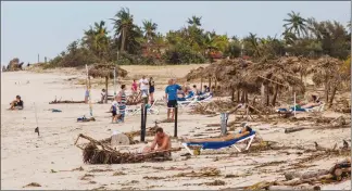  ?? Canadian Press/AP photo ?? Tourists lie on a beach, littered with palms, one day after Hurricane Irma passed the resort area in Varadero, Cuba on Sept. 10.