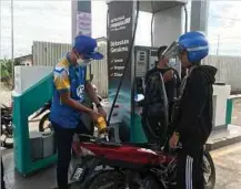  ?? ?? ABAM Peah (berbaju biru) mengisi petrol pada motosikal di sebuah stesen minyak di Kuala Krai, semalam.