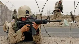 ?? Roberto Schmidt/AFP via Getty Images ?? A military policeman of the Pennsylvan­ia National Guard takes a defensive position at a checkpoint on the outskirts of Fallujah, Iraq, in May 2004.
