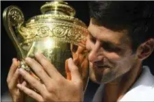  ?? THE ASSOCIATED PRESS ?? Novak Djokovic holds the trophy after defeating Kevin Anderson in the men’s singles final match at the Wimbledon Tennis Championsh­ips in London, Sunday.