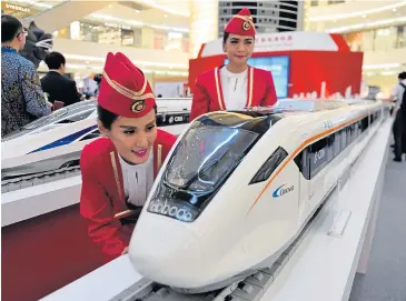  ?? AFP ?? Visitors look at scale models of Chinese-made bullet trains on display at a shopping mall in Jakarta on August 13, 2015.